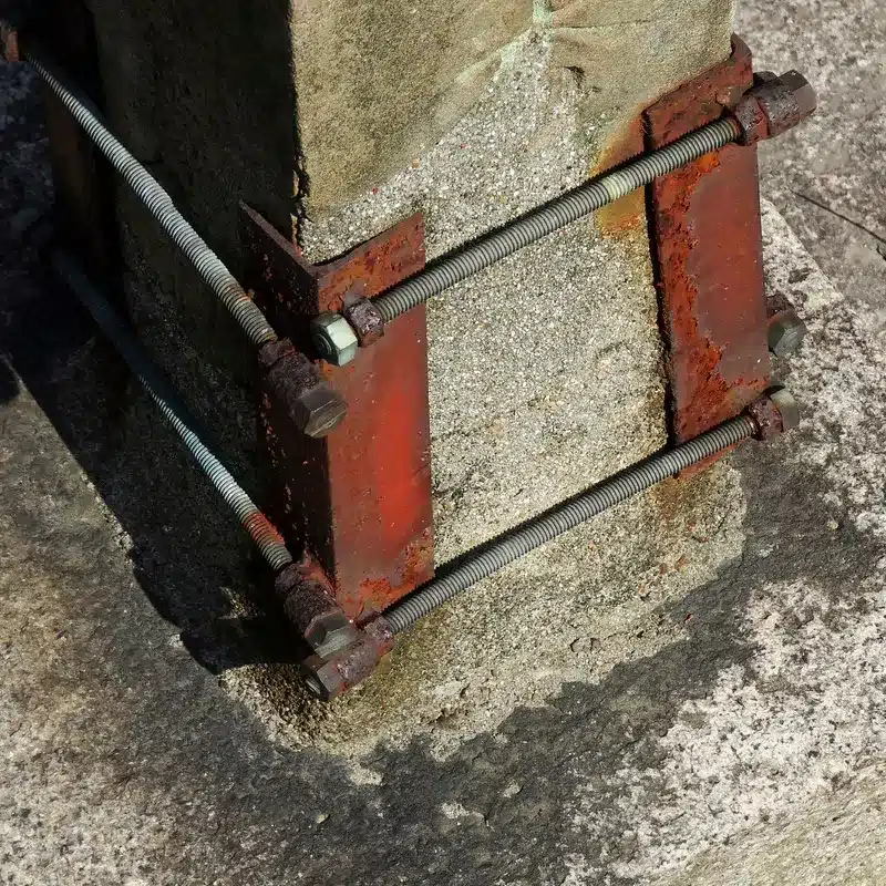 Structure en métal renforçant un monument funéraire en pierre, montrant un travail de restauration pour préserver la stabilité de la sépulture.
