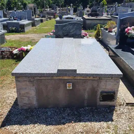 Tombe funéraire en granit gris avec dalle pleine, posée sur un caveau, offrant un hommage sobre et durable aux défunts.